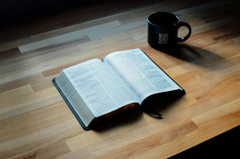 En åpen bibel ved siden av et krus